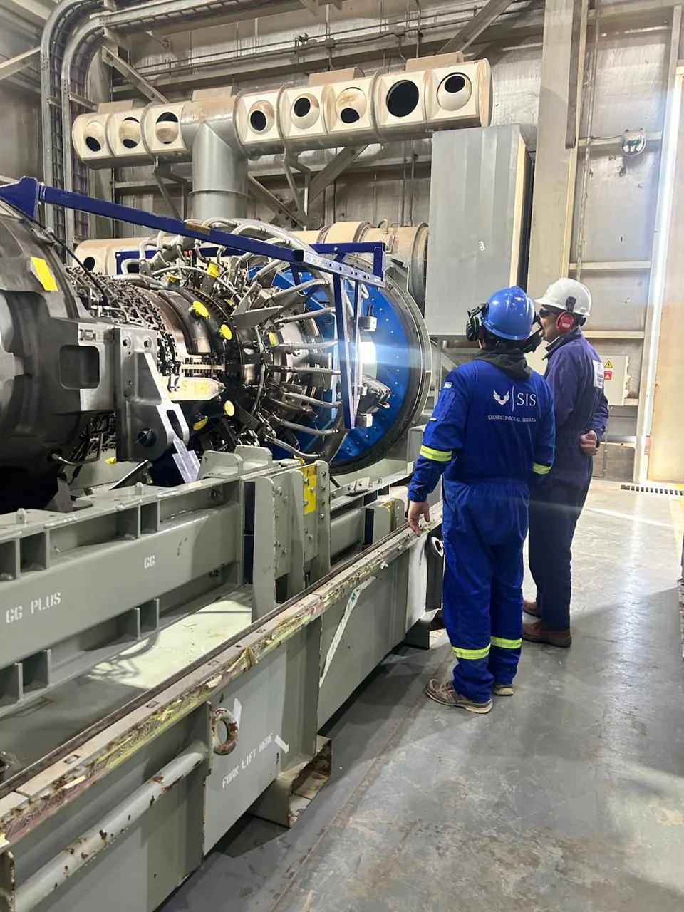 Personal de SIS inspeccionando equipo industrial con indumentaria SIS